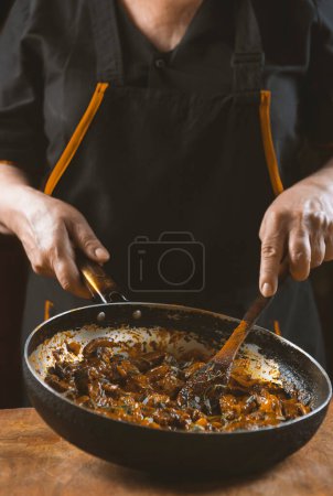 Foto de El cocinero prepara la carne con verduras y cebolla en un tazón. Cocina oriental - Imagen libre de derechos
