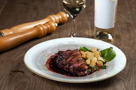 Téléchargez les photos : Poitrine de canard tranchée avec pommes de terre et vin sur table en bois - en image libre de droit