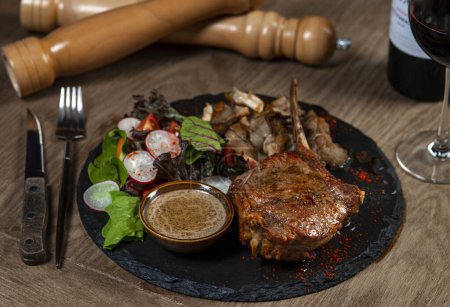 Foto de Filete de cerdo con salsa y ensalada en mesa de madera, primer plano - Imagen libre de derechos
