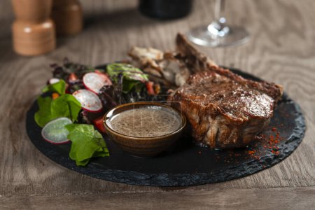 Foto de Filete de cerdo con salsa y ensalada en mesa de madera, primer plano - Imagen libre de derechos