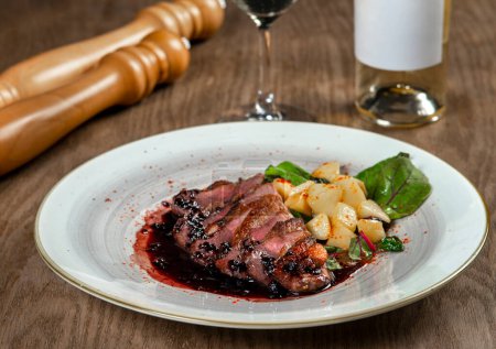 Photo for Sliced duck breast with potatoes and wine on wooden table - Royalty Free Image