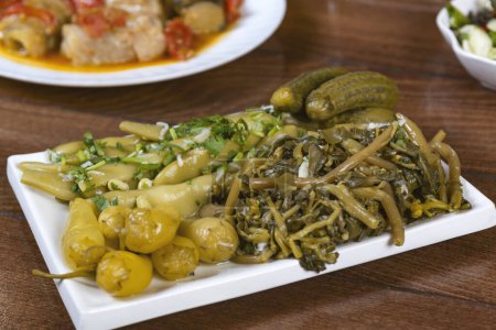 Téléchargez les photos : Concombres marinés et haricots verts dans une assiette sur une table en bois - en image libre de droit