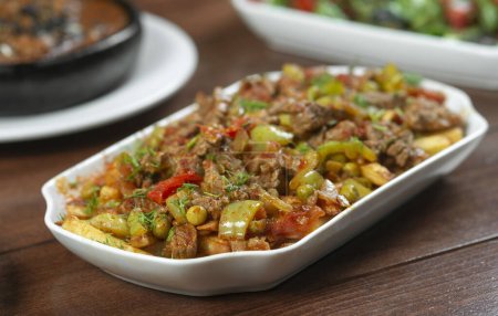 Téléchargez les photos : Boeuf cuit avec des légumes et des herbes dans une assiette blanche. - en image libre de droit