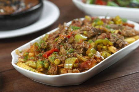 Foto de Carne de res estofada con verduras y hierbas en un plato blanco. - Imagen libre de derechos