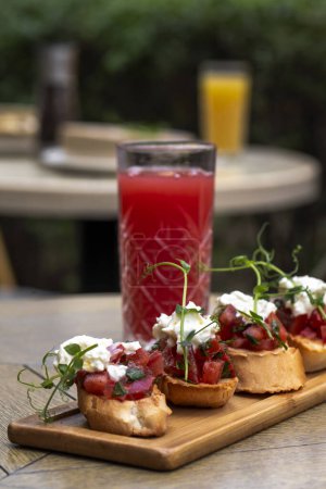 Foto de Canapé con tomate y queso feta sobre una mesa de madera en un restaurante Bruschetta con tomates .mozzarella y rúcula. - Imagen libre de derechos