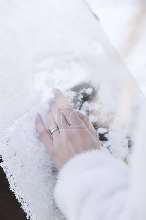 Téléchargez les photos : Gros plan de la main d'une femme tenant une alliance dans la neige - en image libre de droit