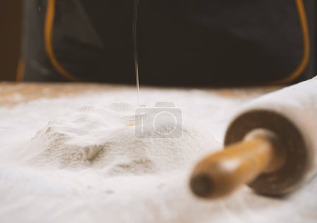 Téléchargez les photos : Gros plan d'un rouleau à pâtisserie et des piles de farine avec du jaune dessus - en image libre de droit