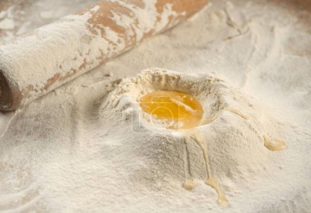 Photo for Close-up of a rolling pin and piles of flour with yolk on it - Royalty Free Image