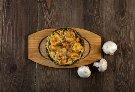 Photo for Homemade julienne with cheese and mushrooms . A hot dish with baked cheese crust on a wooden  table. - Royalty Free Image