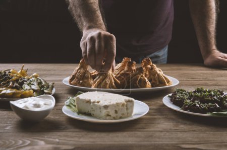Téléchargez les photos : Femme manger traditionnel géorgien dîner, khinkali, fromage et dolma plateau sur table en bois. - en image libre de droit