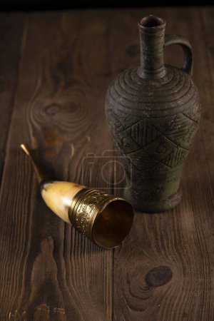 Foto de Vino en ánfora, copa de cuerno, sobre una mesa de madera. Fiesta tradicional georgiana - Imagen libre de derechos