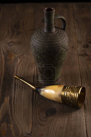 Téléchargez les photos : Du vin dans une amphore, un verre de corne, sur une table en bois. Fête traditionnelle géorgienne - en image libre de droit