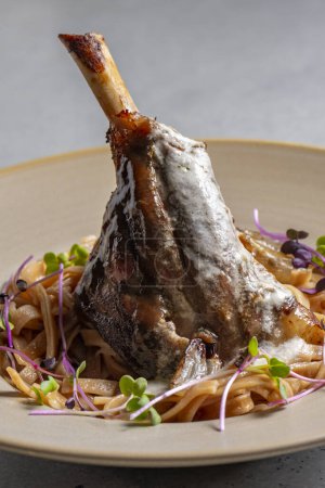 Téléchargez les photos : Lamb chop with noodles, sauce and mustard on a gray background - en image libre de droit