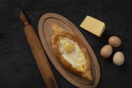 Foto de . adjarian khachapuri de pan plano caucásico con huevo en una madera oscura. Adjarian Khachapuri Pan de queso georgiano - Imagen libre de derechos