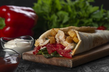 Foto de Shawarma sándwich fresco rollo de, Carne a la parrilla y ensalada con salsa blanca sobre fondo negro. - Imagen libre de derechos