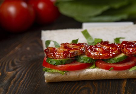 Foto de Sandwich con pollo a la parrilla, lechuga, tomates y aceitunas negras - Imagen libre de derechos