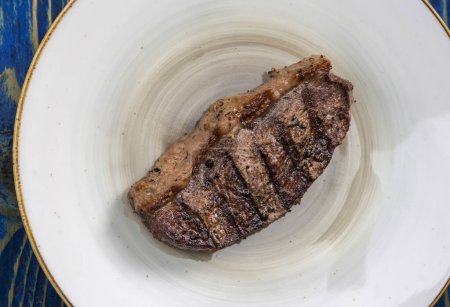 Téléchargez les photos : Viande fraîche grillée.steaks aux épices dans une assiette blanche sur fond de bois bleu - en image libre de droit