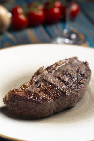 Téléchargez les photos : Steak grillé, tomates cerises sel et poivre sur table en bois. - en image libre de droit