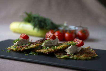 Téléchargez les photos : Crêpes de courgettes au fromage feta, tomates cerises et herbes - en image libre de droit