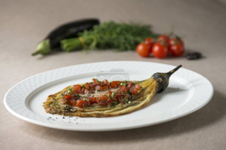 Téléchargez les photos : Aubergine cuite à la tomate et au persil sur une assiette blanche - en image libre de droit