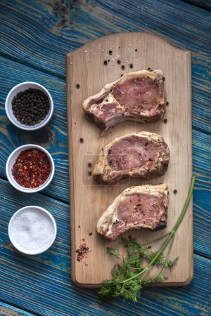Photo for Raw pork ribs with spices and herbs on cutting board on wooden background - Royalty Free Image