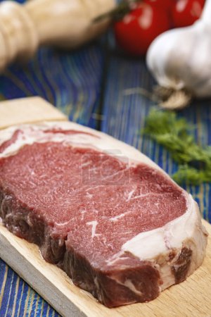Foto de Carne cruda en tabla de cortar con especias sobre fondo de madera - Imagen libre de derechos