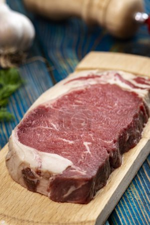 Foto de Carne cruda en tabla de cortar con especias sobre fondo de madera - Imagen libre de derechos
