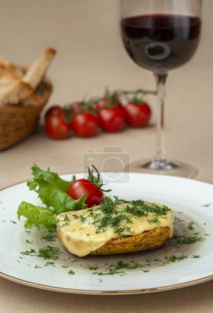 Téléchargez les photos : Pommes de terre cuites au four avec du fromage et des herbes dans une assiette et avec du vin rouge - en image libre de droit