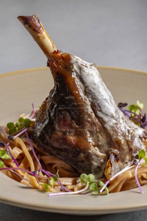 Téléchargez les photos : Lamb chop with noodles, sauce and mustard on a gray background - en image libre de droit