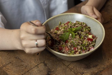 Téléchargez les photos : Salade de taboulé dans un bol sur une table en bois. Salade de quinoa - en image libre de droit