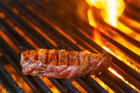 Téléchargez les photos : Tasty steaks de boeuf sur le gril avec des flammes de feu - en image libre de droit