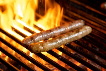 Photo for Grilling sausages on the grill with flames and smoke. - Royalty Free Image