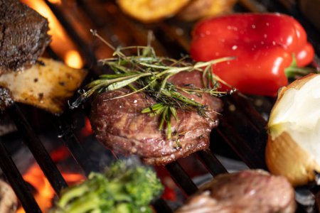 Photo for Beef steak on the grill with vegetables and herbs close-up - Royalty Free Image