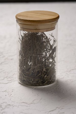 Téléchargez les photos : Herbes séchées dans un bocal en verre sur fond blanc. Concentration sélective. - en image libre de droit