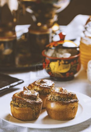 Téléchargez les photos : Petits pains cuits au four avec des graines de pavot sur une nappe blanche. Style ukrainien - en image libre de droit