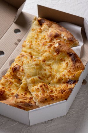 Téléchargez les photos : Morceaux de pizza au fromage dans une boîte en carton sur fond blanc, mise au point sélective. - en image libre de droit