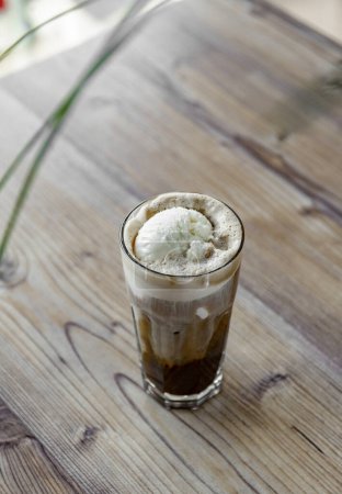 Photo for Iced coffee with whipped cream in a glass on a wooden table - Royalty Free Image