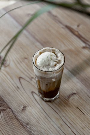 Téléchargez les photos : Café glacé à la crème fouettée dans un verre sur une table en bois - en image libre de droit