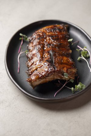 Photo for Grilled ribs with radish and microgreen on a plate - Royalty Free Image