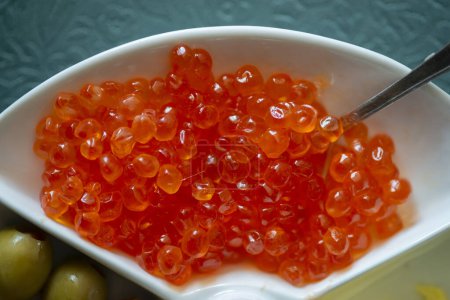 Foto de Caviar rojo en un plato blanco con aceitunas, queso y cuchara - Imagen libre de derechos