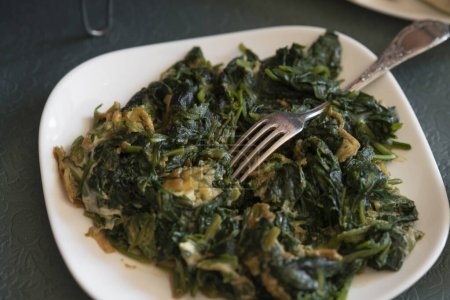 Photo for Stir-fried kale with eggs on a white plate with fork - Royalty Free Image