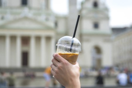Young woman holding take away cup with iced latte