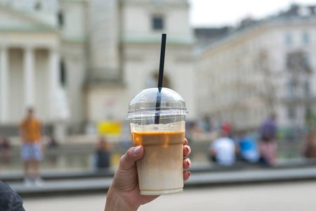 Young woman holding take away cup with iced latte