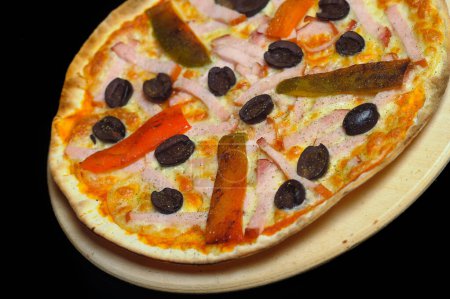 Photo for Pizza with ham, tomato and olives on a black background - Royalty Free Image