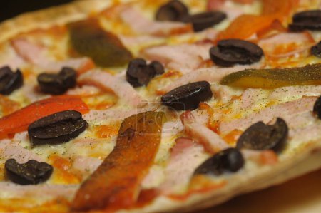 Foto de Pizza con jamón, tomate y aceitunas sobre fondo negro - Imagen libre de derechos