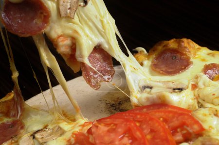 Foto de Pizza con queso mozzarella, jamón y champiñones sobre mesa de madera - Imagen libre de derechos