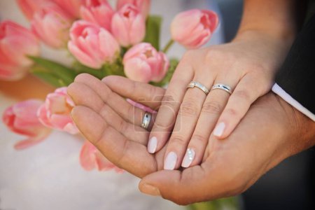 Téléchargez les photos : Wedding rings on the hands in the background with a bouquet of roses - en image libre de droit
