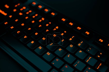 Foto de 3d illustration, close up of the realistic computer or laptop keyboard   with orange neon lights on black background .  Gaming keyboard with LED backlit - Imagen libre de derechos