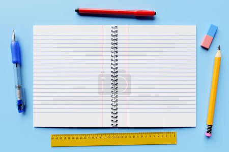Photo for 3 illustration, an open checkered notebook, a blue pen,  pencil, rubber, ruller and marker  on a blue table are ready for the lesson. Stationery.Back to school - Royalty Free Image