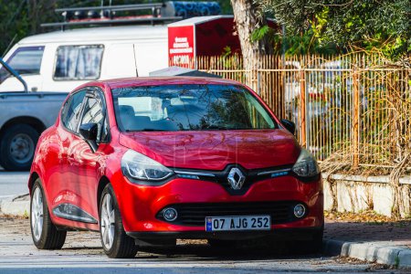 Foto de Side, Turkey -January 21, 2023: red Renault Clio está aparcado en la calle en un cálido día de verano con el telón de fondo de un edificio - Imagen libre de derechos